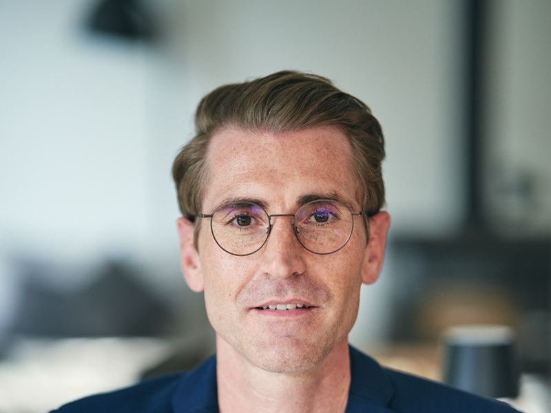 Business Portrait ab 790 Euro: Mann mit Brille im blauen Sakko, Headshot für LinkedIn und Website