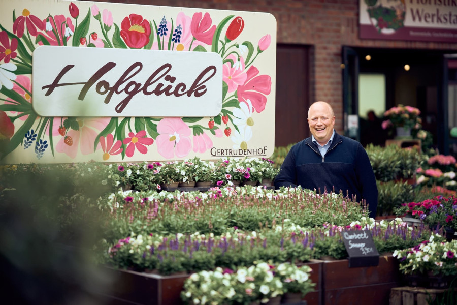 Personal Branding: Unternehmer vor dem Hofglück-Schild im Gartencenter Gertrudenhof
